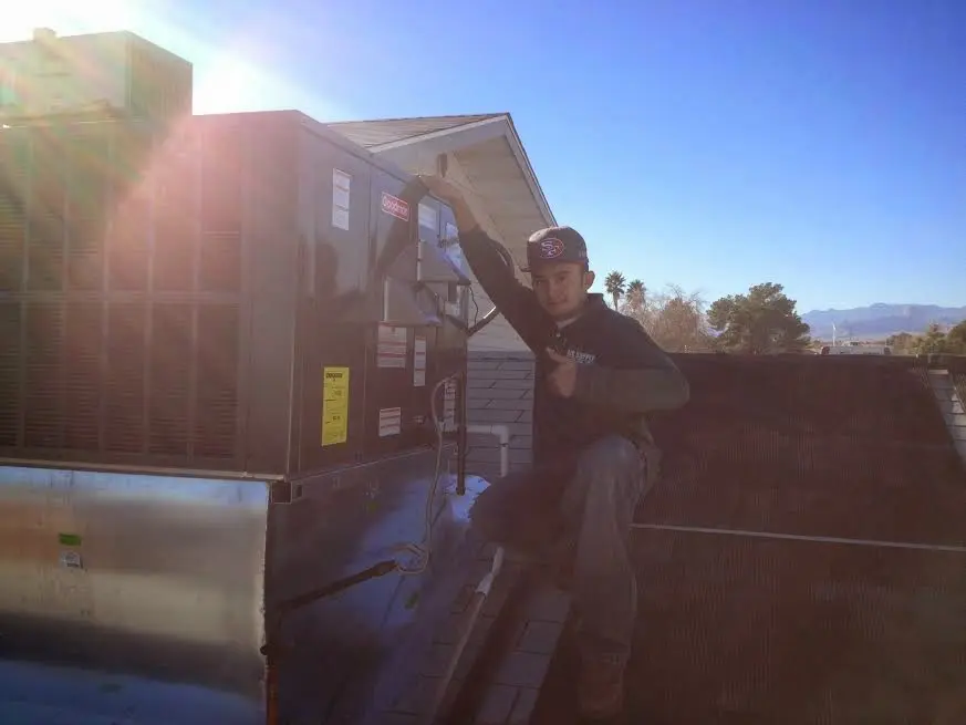 HVAC technician performing Heat Pump Repair on a rooftop unit in Forney